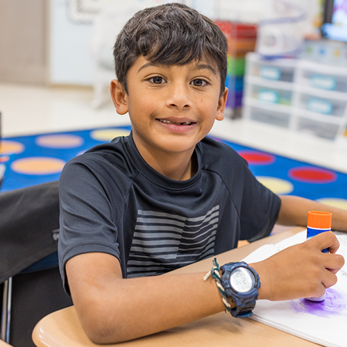 Elementary students arm in arm smiling outside of the school building
